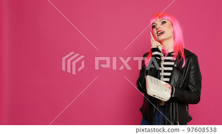 Smiling cool girl chatting on retro telephone line, feeling happy and confident talking on landline phone. Remote conversation on stationary cellphone call, cord communication in studio. 97608538