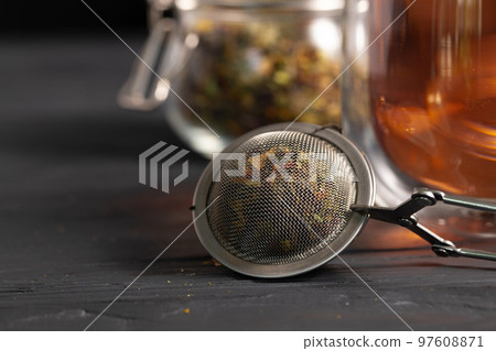 Metal tea strainer on black wooden table Metal tea strainer on black wooden table 97608871