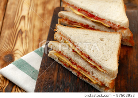 Sandwiches cut into halves on wooden cutting board with napkin Sandwiches cut into halves on wooden cutting board with napkin 97608958