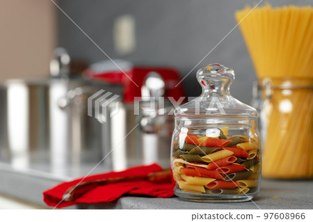 Glass jar of dry pasta on kitchen counter Glass jar of dry pasta on kitchen counter 97608966