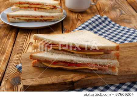 Sandwiches cut into halves on wooden cutting board with napkin 97609204