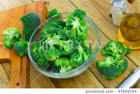 Fresh chopped broccoli in glass bowl with knife, salt and olive oil Fresh chopped broccoli in glass bowl with knife, salt and olive oil 97609264