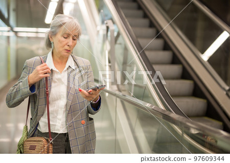 Mature businesswoman using smartphone in office building Mature businesswoman using smartphone in office building 97609344