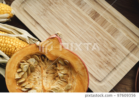 Corn cob and pumpkin on brown wooden board Corn cob and pumpkin on brown wooden board 97609356