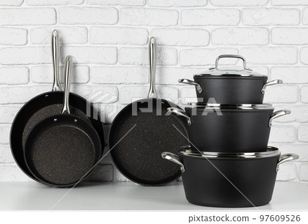 Set of cookware on table against white brick wall 97609526