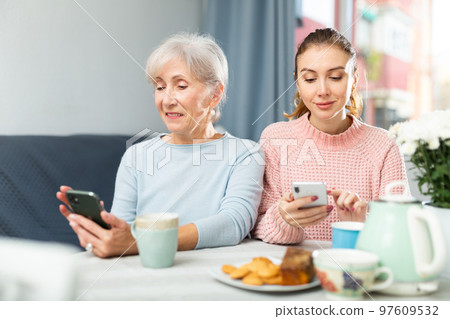 Senior woman and her granddaughter using smartphones at home Senior woman and her granddaughter using smartphones at home 97609532