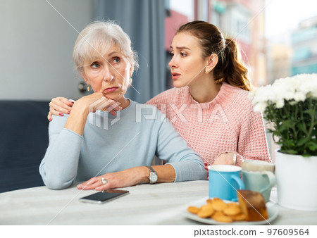 Girl asking for forgiveness from offended mother at home table 97609564
