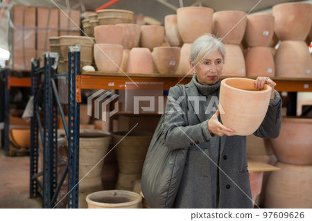 Elderly woman looking for flower pots in hypermarket Elderly woman looking for flower pots in hypermarket 97609626