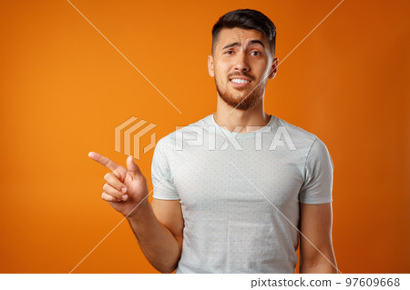 Young handsome man standing and pointing fingers to the side 97609668