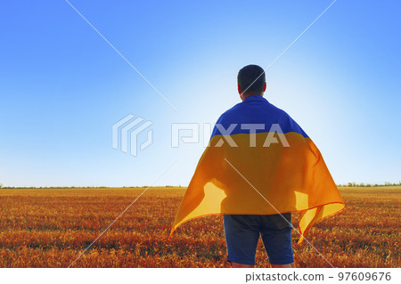 Man with a flag of Ukraine standing in field 97609676