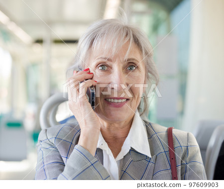 Portrait of senior woman talking on phone in tram 97609903