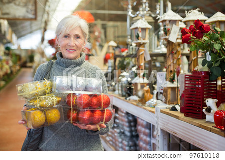 Senior woman with christmas balls in store Senior woman with christmas balls in store 97610118