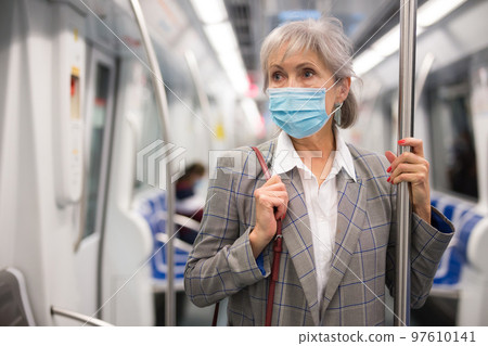Mature woman in face mask inside subway train Mature woman in face mask inside subway train 97610141