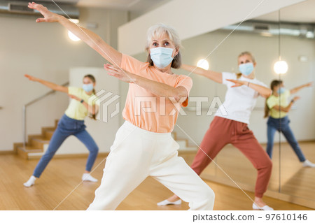 Senior woman in mask performing contemporary dance in studio Senior woman in mask performing contemporary dance in studio 97610146