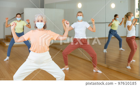 Family in protective masks are engaged in sports dancing in gym Family in protective masks are engaged in sports dancing in gym 97610185
