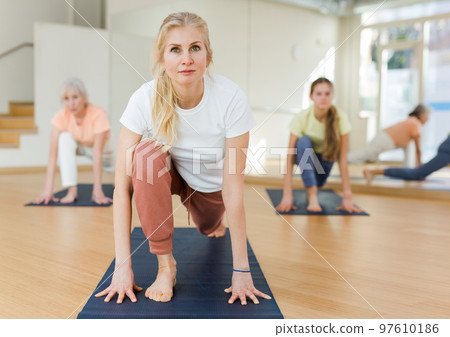 Sport and healthy lifestyle concept - females doing stretching workout during group training in studio Sport and healthy lifestyle concept - females doing stretching workout during group training in studio 97610186