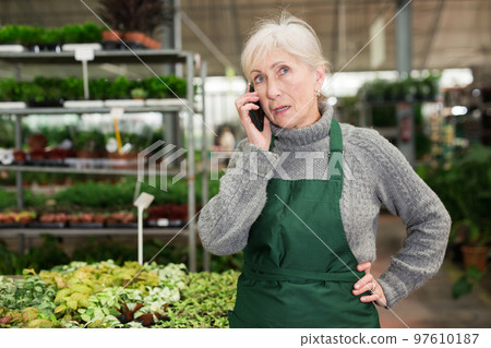 Focused woman garden shop owner having phone conversation Focused woman garden shop owner having phone conversation 97610187