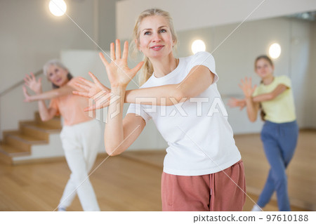 Woman dancing modern dance with other women during group training in classroom 97610188