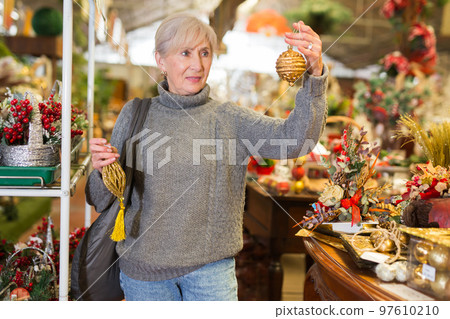 Senior woman choosing christmas decorations in store Senior woman choosing christmas decorations in store 97610210