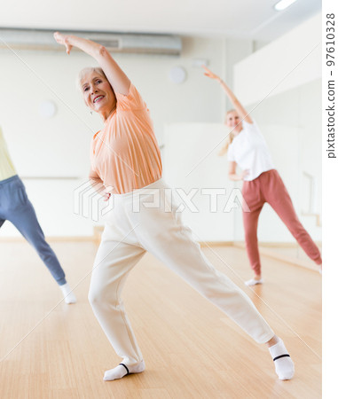 Woman dancing modern dance with other women during group training in classroom 97610328