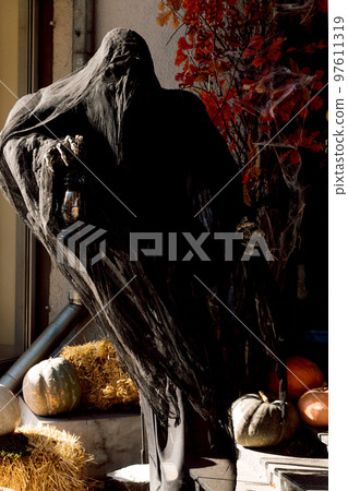 Dead man in black near pumpkins cemetery on Halloween 97611319