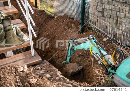 Mini excavator digs a trench to lay pipes. Close up of an excavator digging a deep trench. An excavator digs a trench in the countryside to lay a water pipe. Slow motion Mini excavator digs a trench to lay pipes. Close up of an excavator digging a deep trench. An excavator digs a trench in the countryside to lay a water pipe. Slow motion 97614341