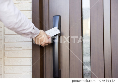 A man's hand holding a card-type key to unlock the front door A man's hand holding a card-type key to unlock the front door 97615412