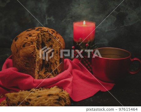 Panetonne with tea and a candle in the far right on a black concrete background Panetonne with tea and a candle in the far right on a black concrete background 97615464