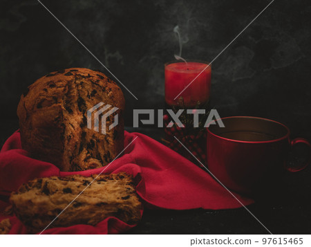 pannetona with tea and a candle in the far right on a black concrete background pannetona with tea and a candle in the far right on a black concrete background 97615465
