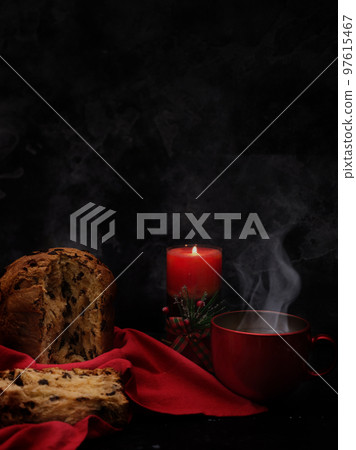 pannetona with tea and a candle in the far right on a black concrete background pannetona with tea and a candle in the far right on a black concrete background 97615467