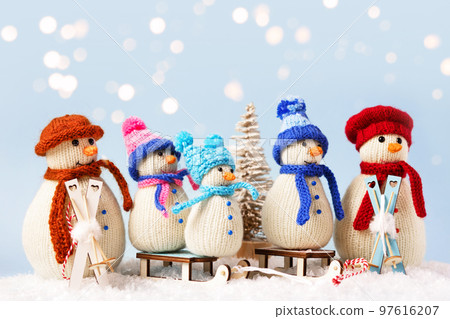 Knitted snowmen in colorful hats and scarves on a blue background. The concept of Christmas, New Year and winter fairy tale. Flat lay 97616207