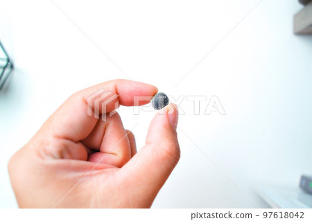 Coin cell or button cell battery LR1130 in hand Coin cell or button cell battery LR1130 in hand 97618042