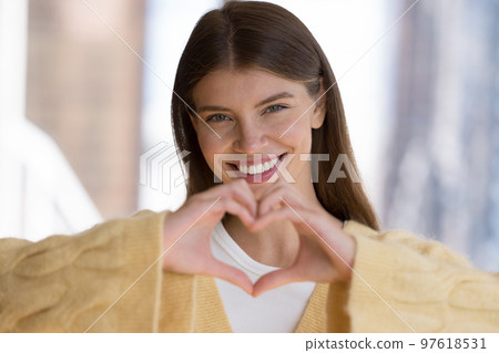 Happy carefree pretty girl in casual showing finger heart shape 97618531