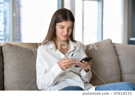Engaged digital addict girl using two smartphones for data Engaged digital addict girl using two smartphones for data 97618533