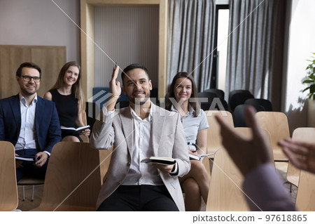 Smiling business training participant raising hand having question to speaker Smiling business training participant raising hand having question to speaker 97618865