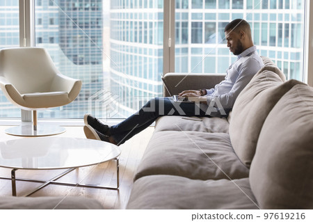 Serious handsome African freelance professional man typing on laptop Serious handsome African freelance professional man typing on laptop 97619216