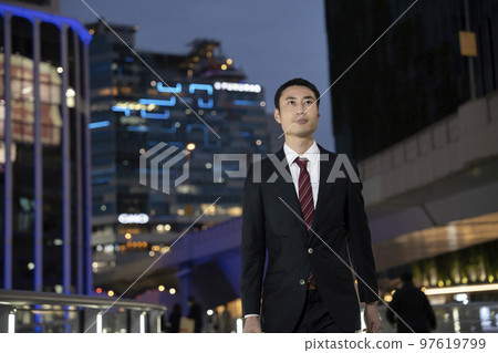 Businessman in a suit walking in the night city 97619799