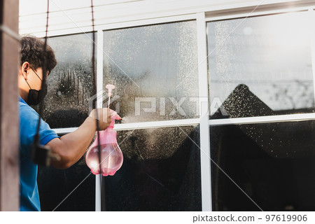 Unidentified man wrapper tinting a window with tinted foil using foggy spray. 97619906