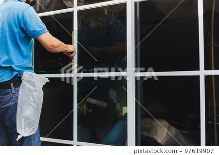 Worker use scraper cleaning window before installing tinting film. Worker use scraper cleaning window before installing tinting film. 97619907