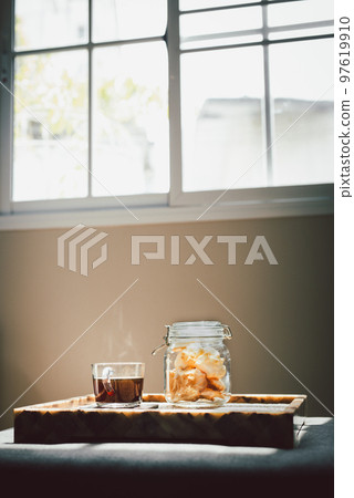 Glass of black coffee with jar of cookies in living room. Glass of black coffee with jar of cookies in living room. 97619910