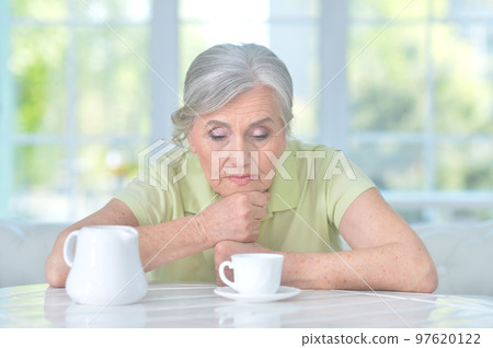 sad old woman drinking tea at home sad old woman drinking tea at home 97620122