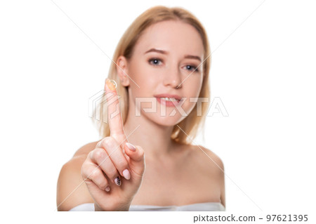 Focus on contact lens on finger of young woman. Young woman holding contact lens on finger in front of her face. Woman holding contact lens on white background. Focus on contact lens on finger of young woman. Young woman holding contact lens on finger in front of her face. Woman holding contact lens on white background. 97621395