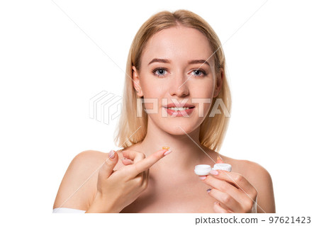 Young woman holding contact lenses cases and lens in front of her face on white background 97621423