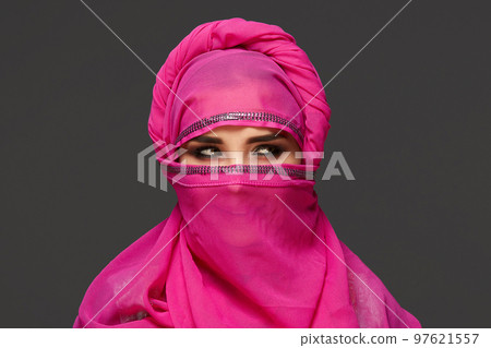 Close-up shot of a young charming woman wearing the pink hijab decorated with sequins. Arabic style. 97621557