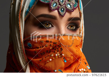 Studio shot of a chrming female wearing the colorful hijab decorated with sequins and jewelry. Arabic style. Studio shot of a chrming female wearing the colorful hijab decorated with sequins and jewelry. Arabic style. 97621615