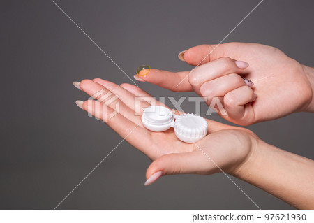 Contact eye lens. Close-up of woman hands holding white eyelense container. Contact eye lens. Close-up of woman hands holding white eyelense container. 97621930