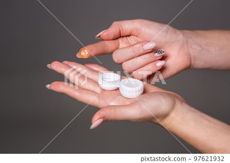 Contact eye lens. Close-up of woman hands holding white eyelense container. Contact eye lens. Close-up of woman hands holding white eyelense container. 97621932