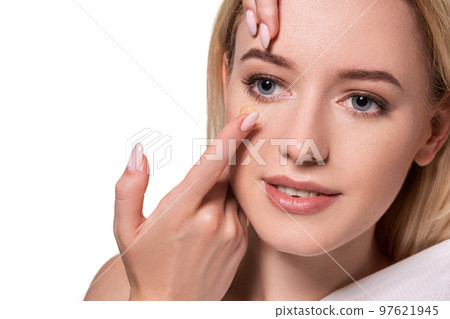 Young woman holding contact lens on index finger with copy space. Close up face of healthy beautiful woman about to wear contact lens. Young woman holding contact lens on index finger with copy space. Close up face of healthy beautiful woman about to wear contact lens. 97621945