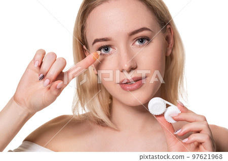 Young woman holding contact lenses cases and lens in front of her face on white background 97621968