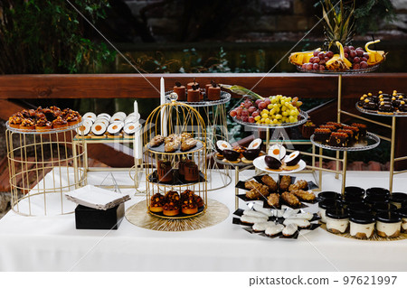 Many cakes standing among the candy bar. Sweet table. Banquet table. Holiday food and sweet festive table. Many cakes standing among the candy bar. Sweet table. Banquet table. Holiday food and sweet festive table. 97621997